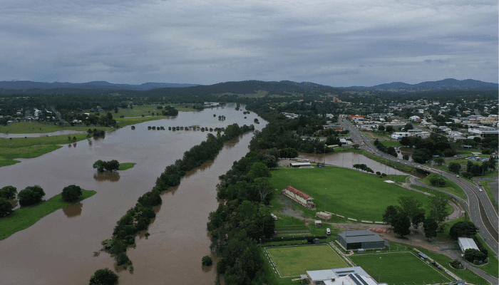Aerial view of a river winding through green fields and a town with roads and buildings