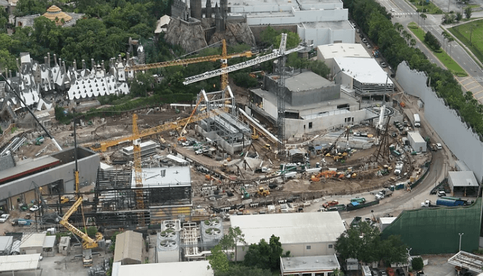 Aerial construction site with multiple cranes, circular foundation, and machinery spread across the area