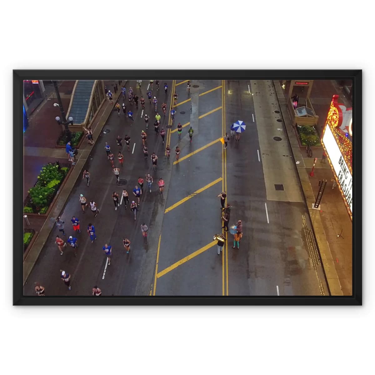 Aerial view of a crowded city street race with runners on a wet road and yellow lane markings