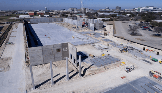 Aerial view of a construction site with concrete walls, steel columns, and workers