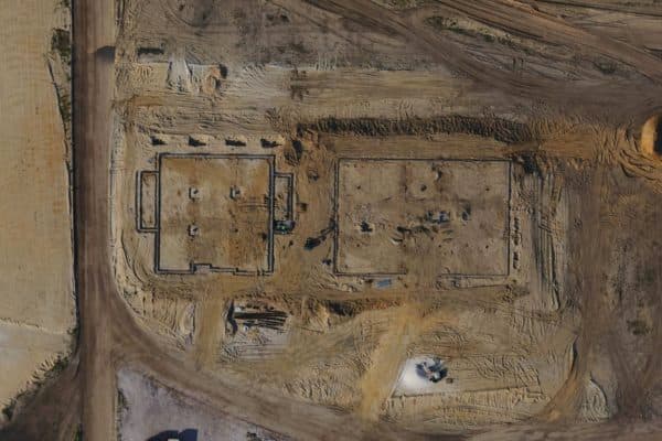 Aerial view of a construction site with two rectangular building footprints and dirt roads