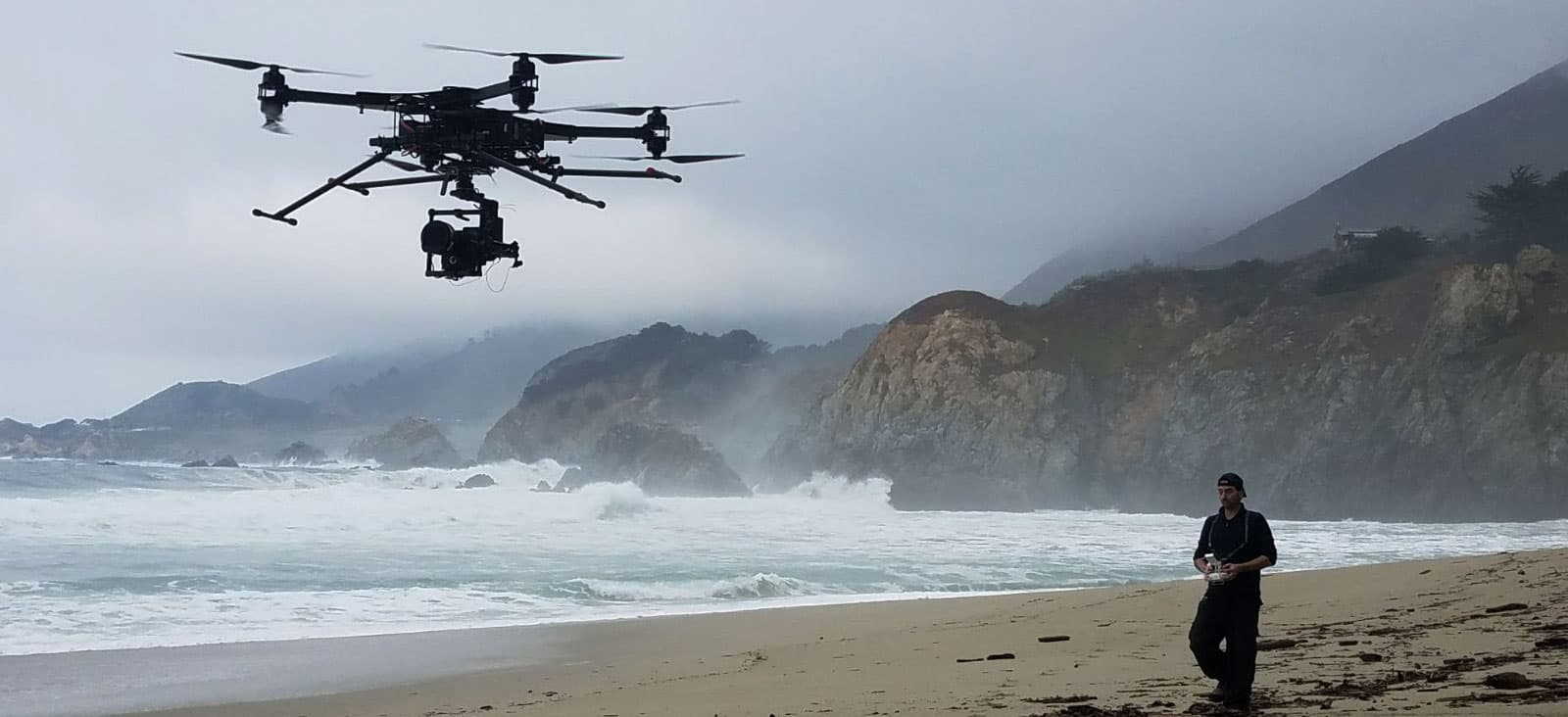 Kaizen Aerospace portfolio: multi-rotor drone hovering above a beach as a man with a controller stands nearby