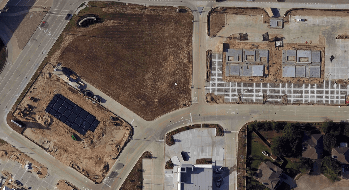 Aerial view of a construction site with dark solar panels and surrounding roads