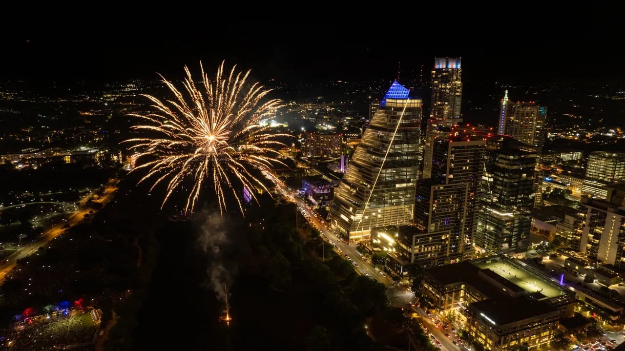 Night aerial view of a city skyline with fireworks and illuminated streets