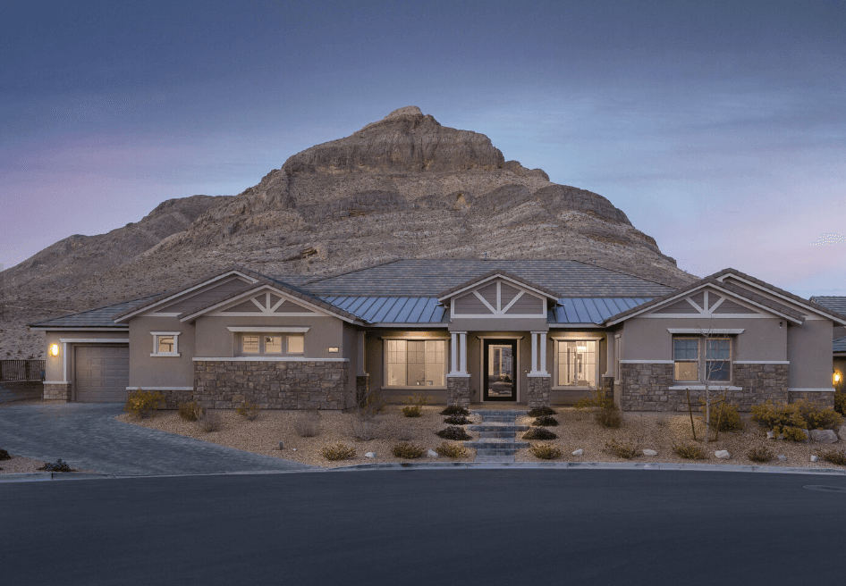 Front view of a single-story stucco house with stone accents and a mountain backdrop at dusk