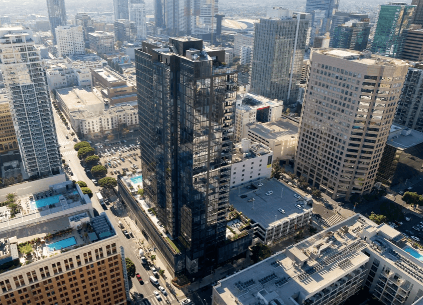 Aerial view of a dense downtown with a tall dark glass skyscraper among other high rise buildings