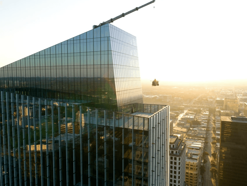 Glass-fronted skyscraper with a small drone hovering over the city at sunset