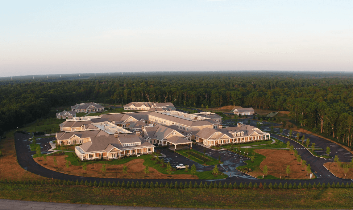 Aerial view of a large campus-style building complex with gray roofs and surrounding parking