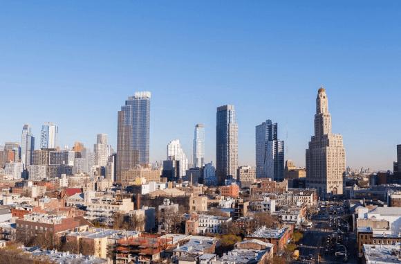City skyline with tall skyscrapers and a grid of low-rise buildings under a clear blue sky