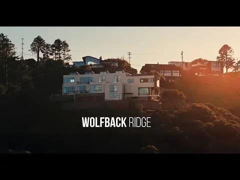 Modern multi-story house on a hillside with trees and a Wolfback Ridge text overlay