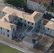 Aerial view of tan-roofed buildings under construction and surrounding neighborhood houses