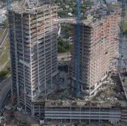 Two high-rise buildings under construction with scaffolding and cranes seen from above