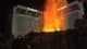 Glowing orange flames and smoke rising from a dark rock formation