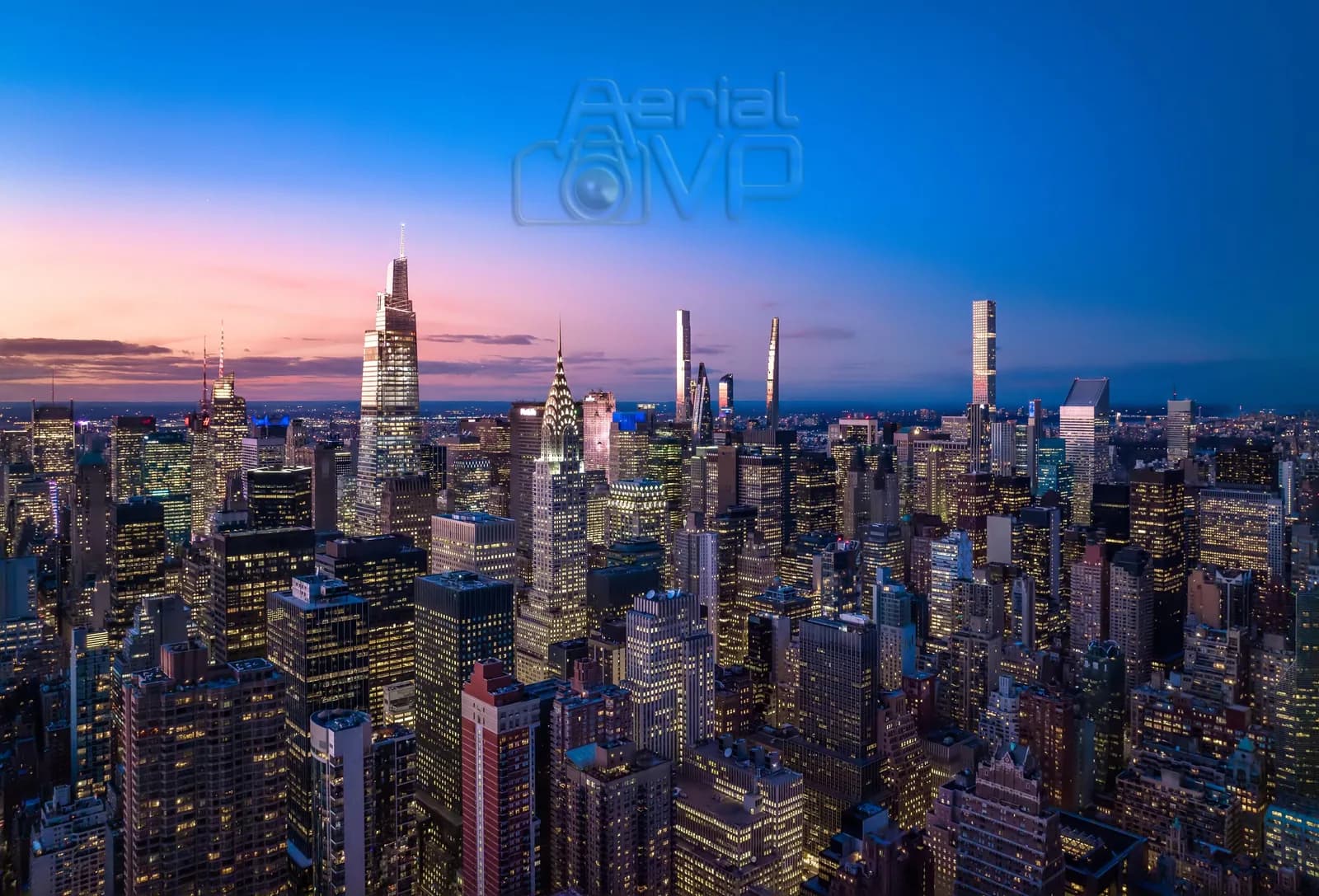City skyline at dusk with tall illuminated skyscrapers and a pink to blue gradient sky