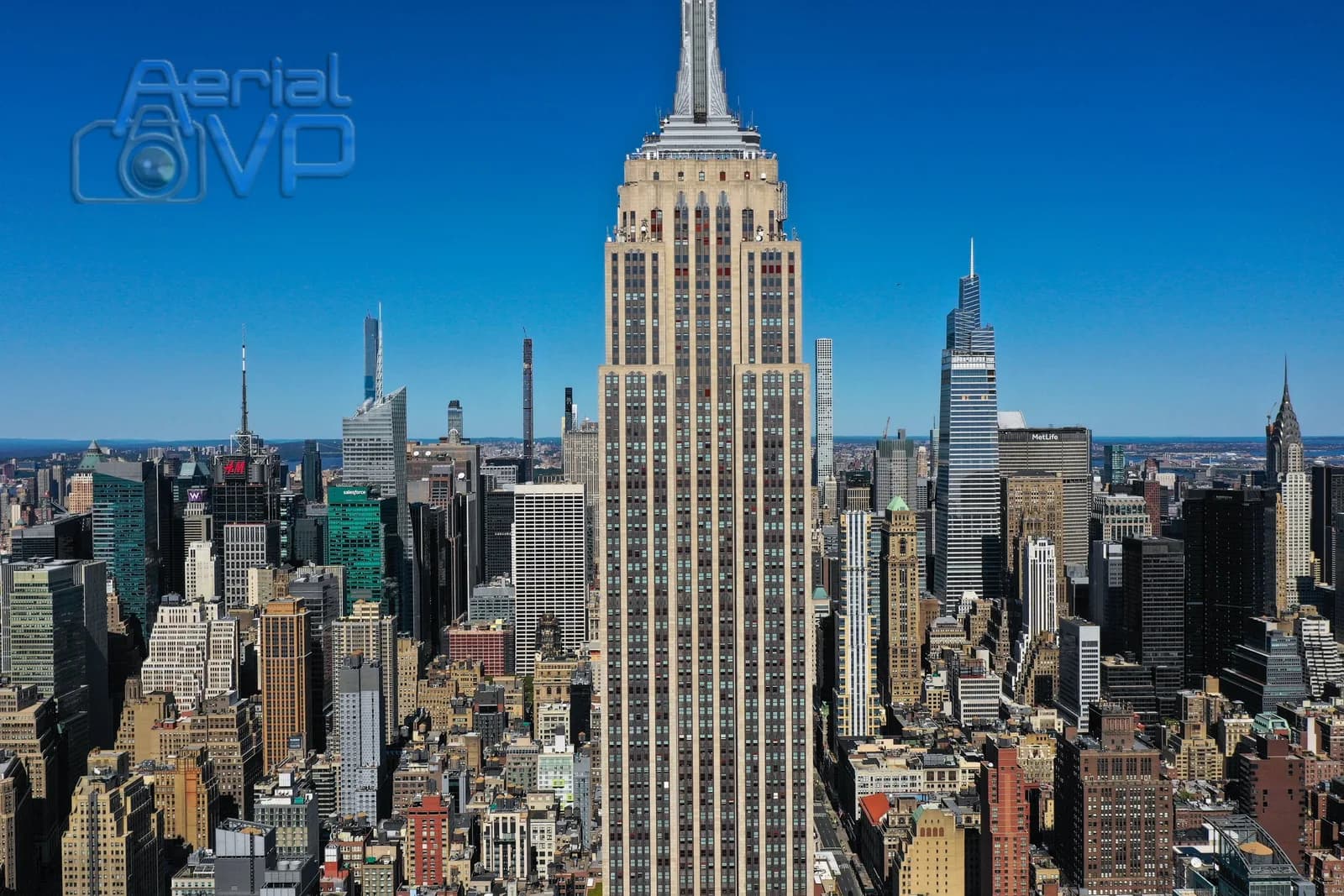 Aerial view of New York City skyline with a central tall building and blue sky, watermark Aerial VP
