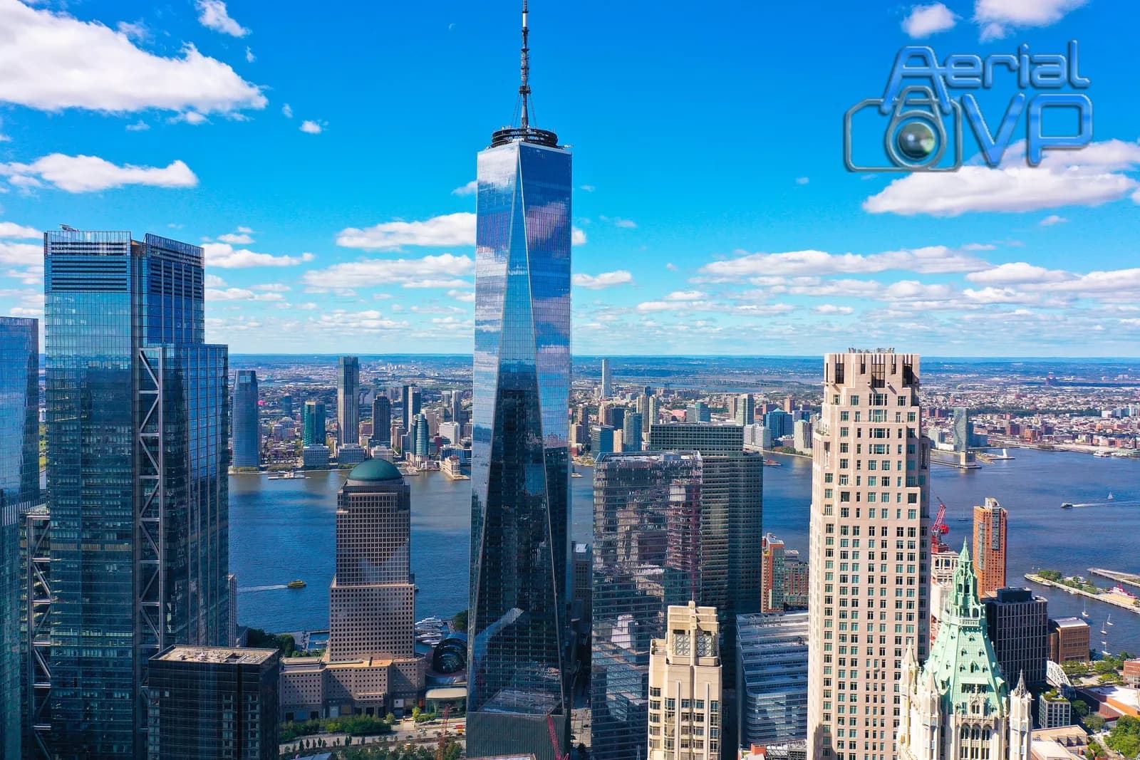 Aerial shot of a city skyline with glass skyscrapers and a river under a blue sky with clouds