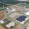 Aerial view of a campus-like industrial complex with multiple white buildings and rooftop solar panels