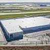 Aerial view of a large warehouse complex with a white roof and surrounding parking areas