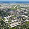 Aerial view of a grid of white-roofed buildings with roads and green spaces