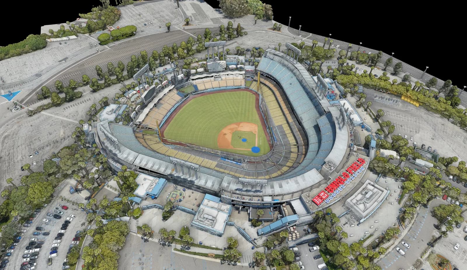 Aerial view of a baseball stadium with green field, curved stands, and surrounding parking and trees