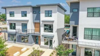Aerial view of modern white and gray townhouses with balconies and landscaped front yards