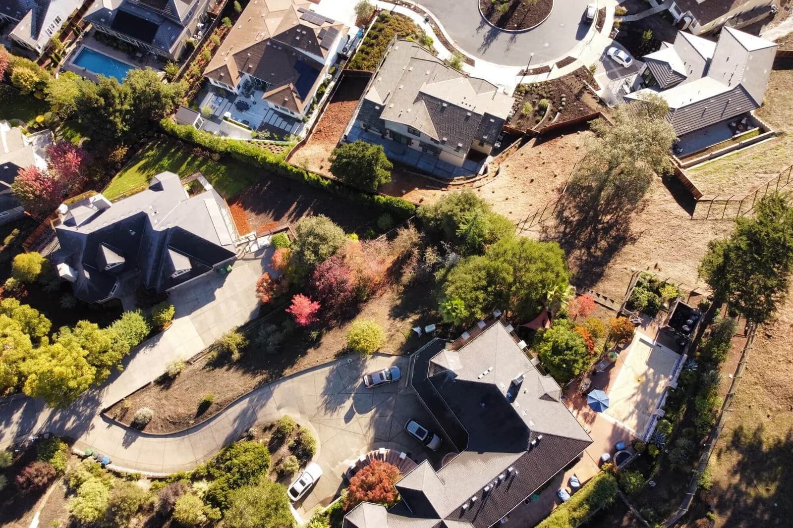 Aerial view of a suburban neighborhood with large houses, curved roads, and trees