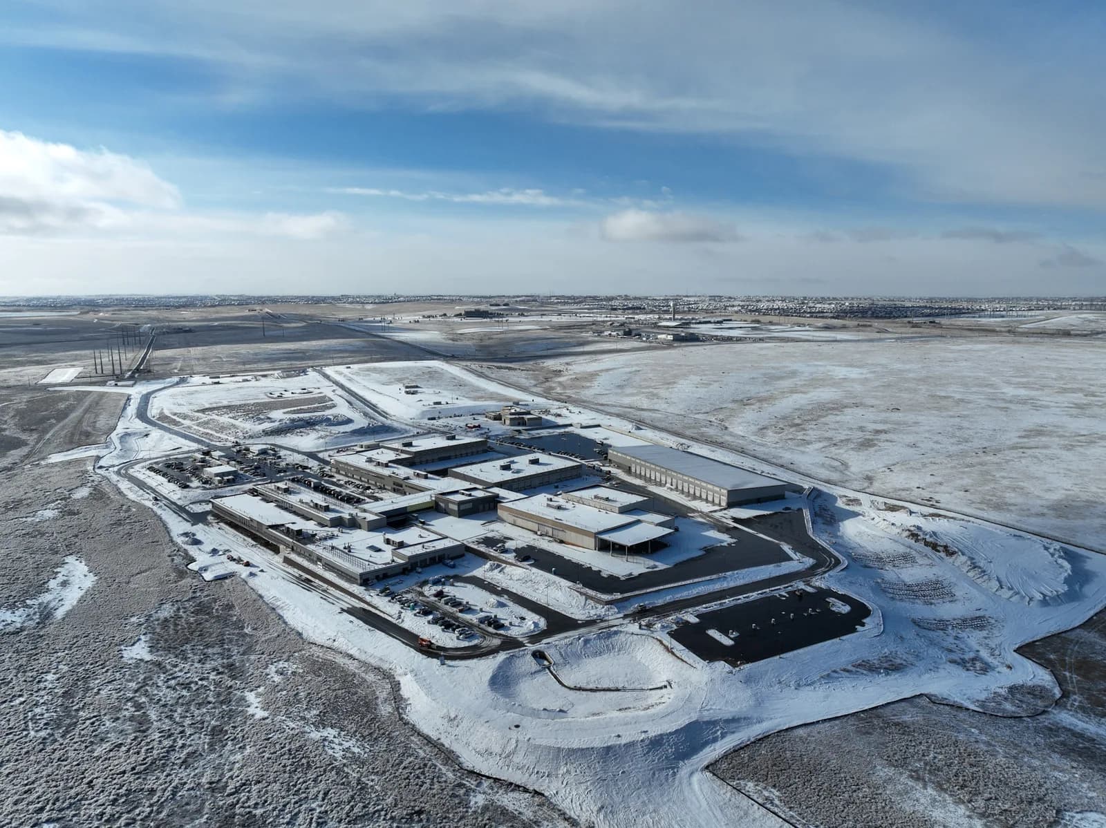 Aerial view of a snow-covered industrial complex with multiple warehouses and a network of roads