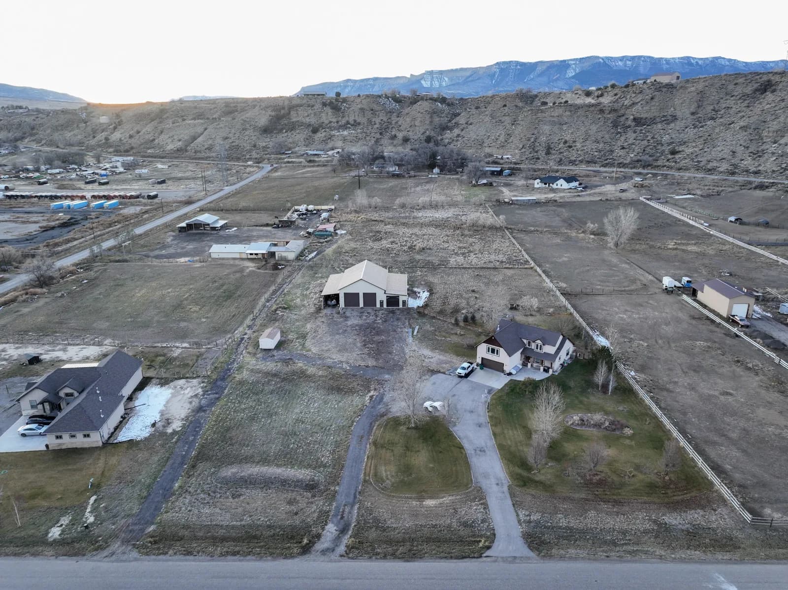 Aerial view of a rural neighborhood with houses, yards, fences, roads and a mountain range in the background