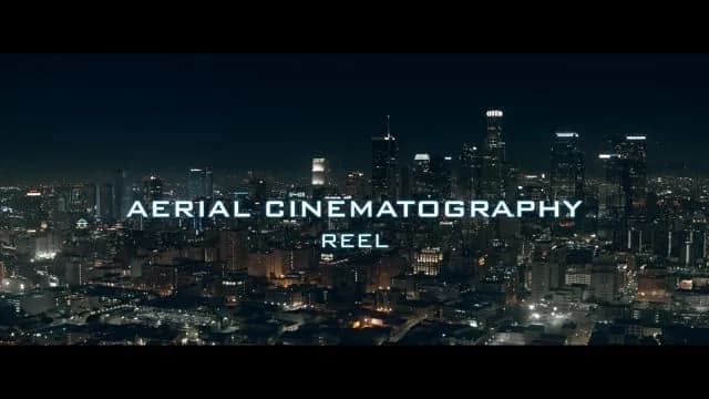 Nighttime city skyline with lit buildings and bold text AERIAL CINEMATOGRAPHY REEL across the center