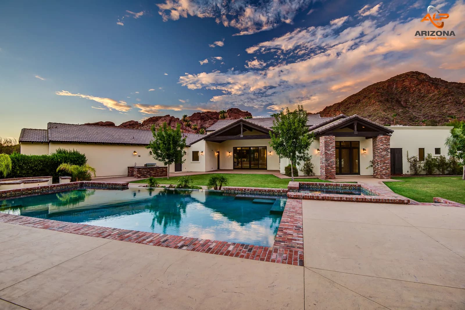 Single-story house with patio, brick-edged swimming pool and mountains at sunset