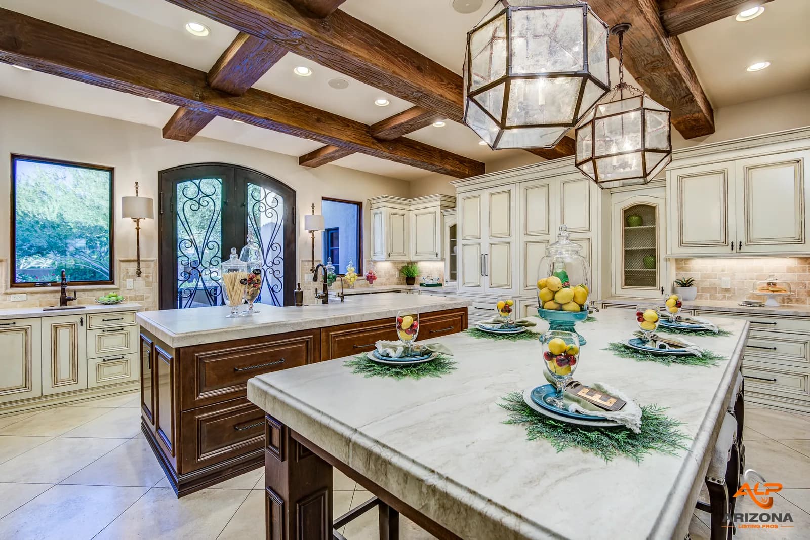 Bright gourmet kitchen with large marble island, wood beam ceiling, pendant lanterns, and place settings