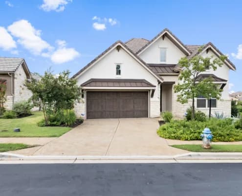 Two-story beige house with a brown garage door, driveway, lawn, and blue fire hydrant by the sidewalk