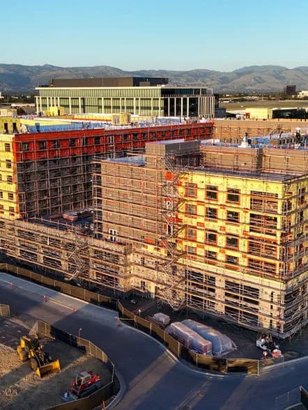 Construction site with several scaffolded, multi-story buildings and a road in the foreground