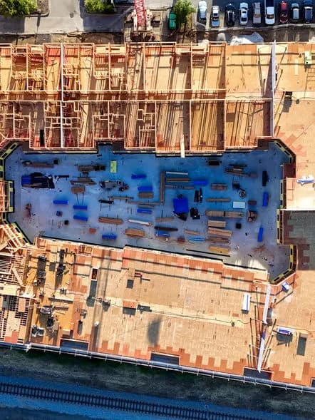 Aerial view of a construction site with orange framing surrounding a blue rectangular area