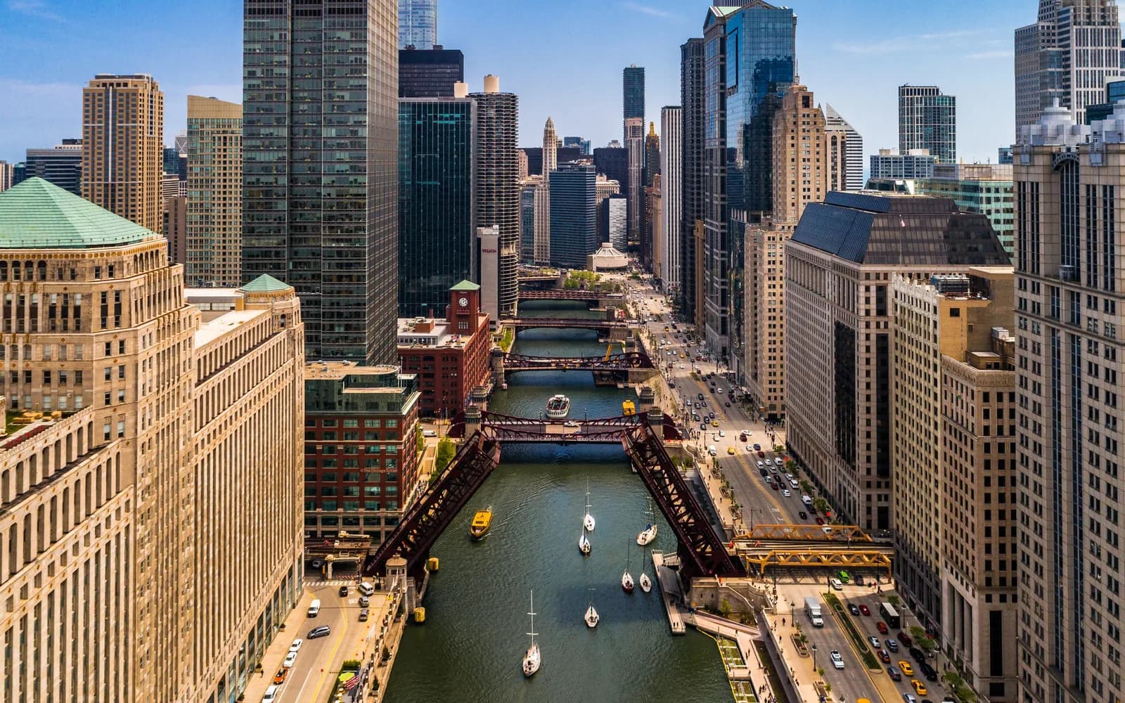 Aerial view of a downtown city with a river, red bridges, boats, and tall buildings on both sides