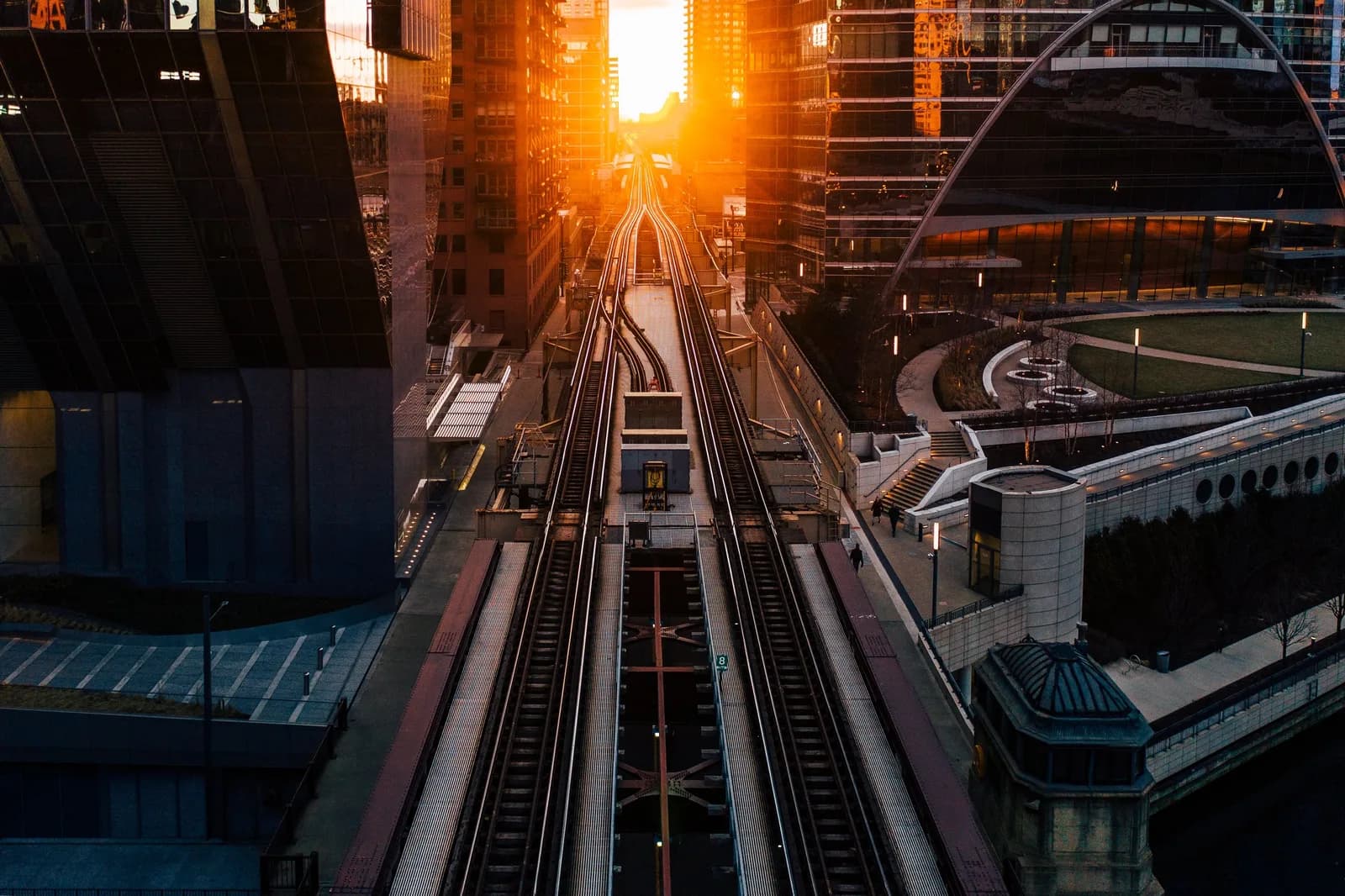 Sunset over elevated railway tracks between glass skyscrapers in a city center