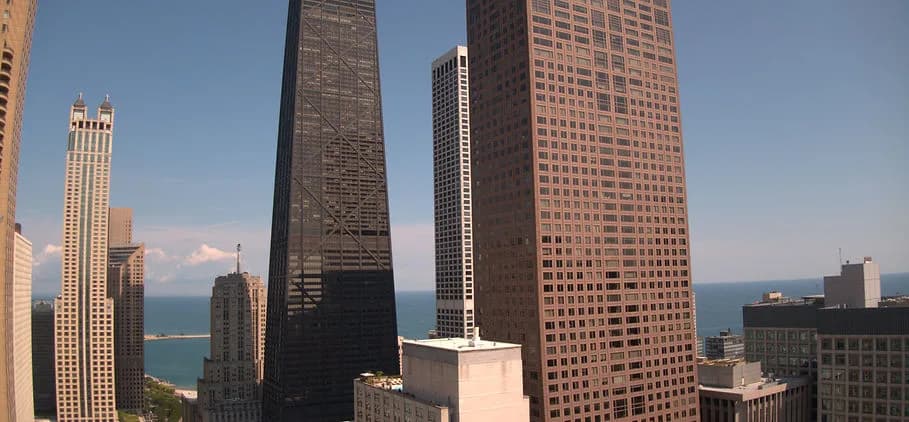 City skyline with tall skyscrapers and a distant body of water under a clear blue sky