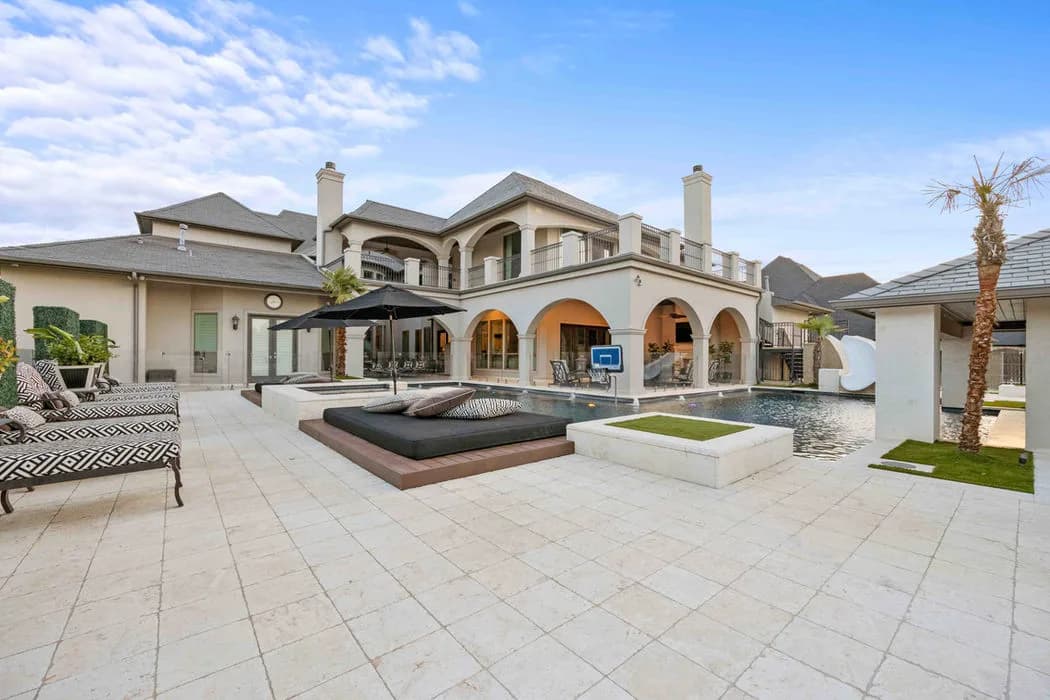Two-story villa with arched veranda, pool, and outdoor lounge on a tiled patio