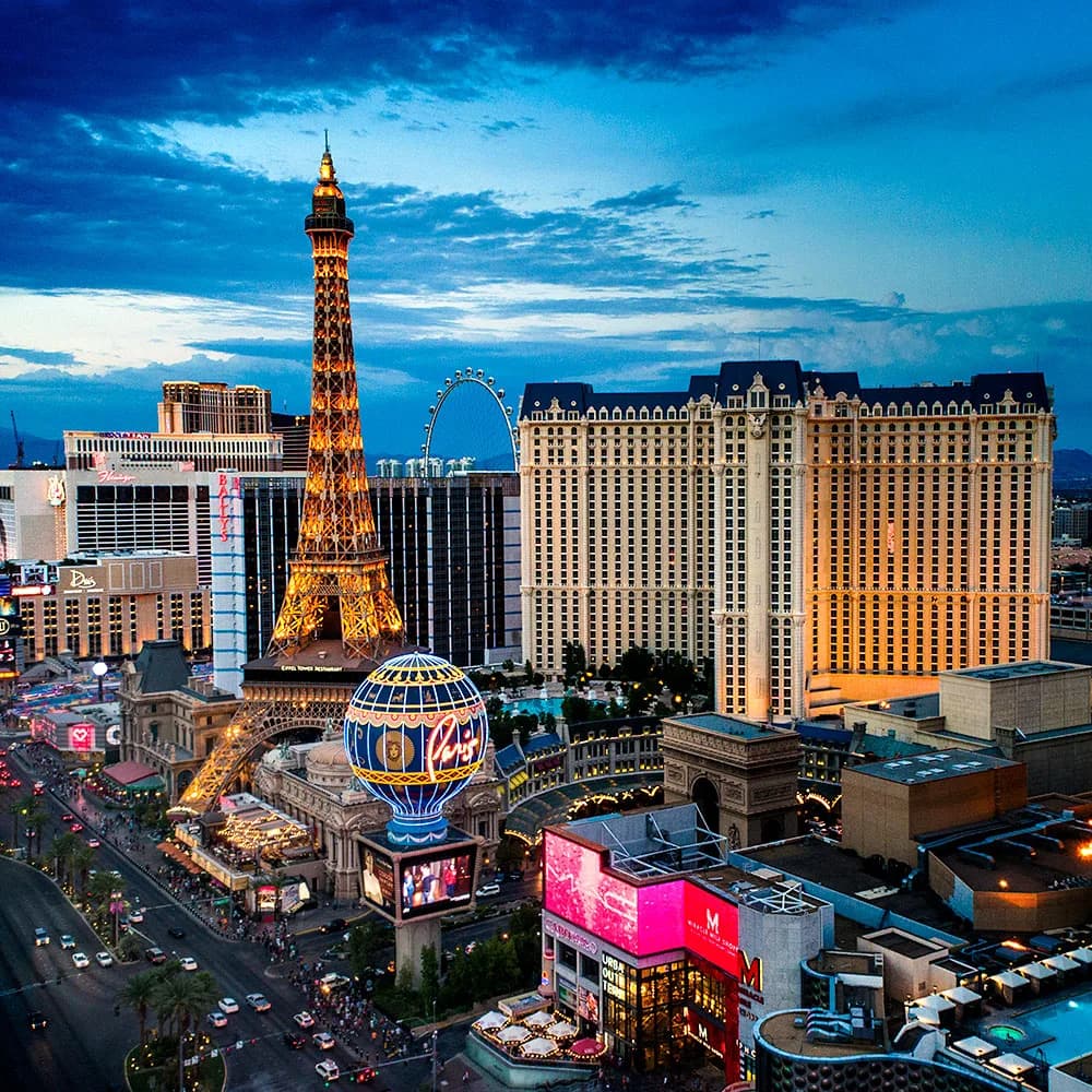 Aerial view of the Las Vegas Strip at dusk with the Eiffel Tower replica, Paris balloon, and hotels