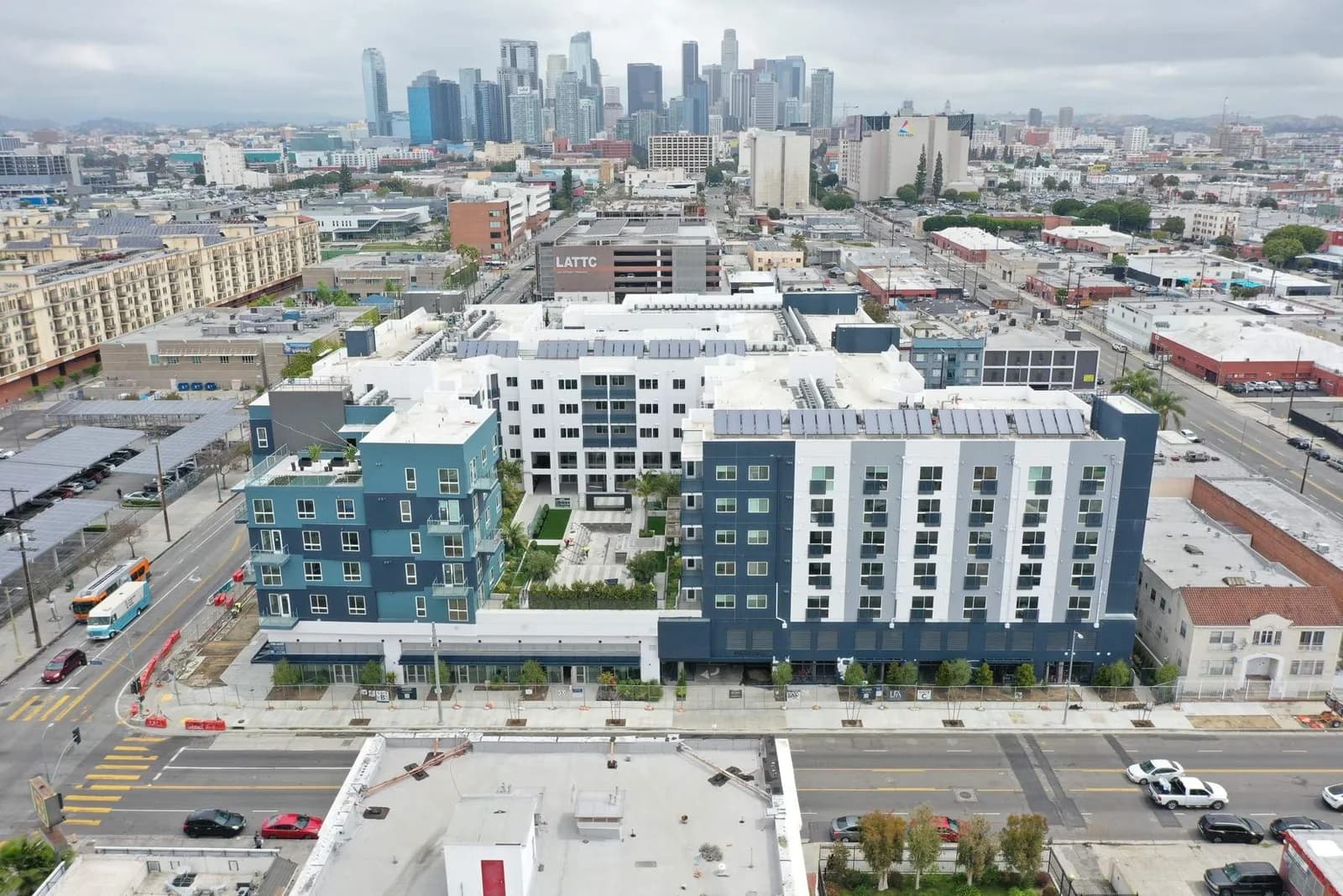 Aerial view of a city with blue and white apartment buildings in the foreground and a downtown skyline beyond