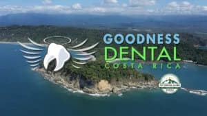 Aerial view of a coast with blue ocean; overlay shows the Goodness Dental Costa Rica logo with a winged tooth