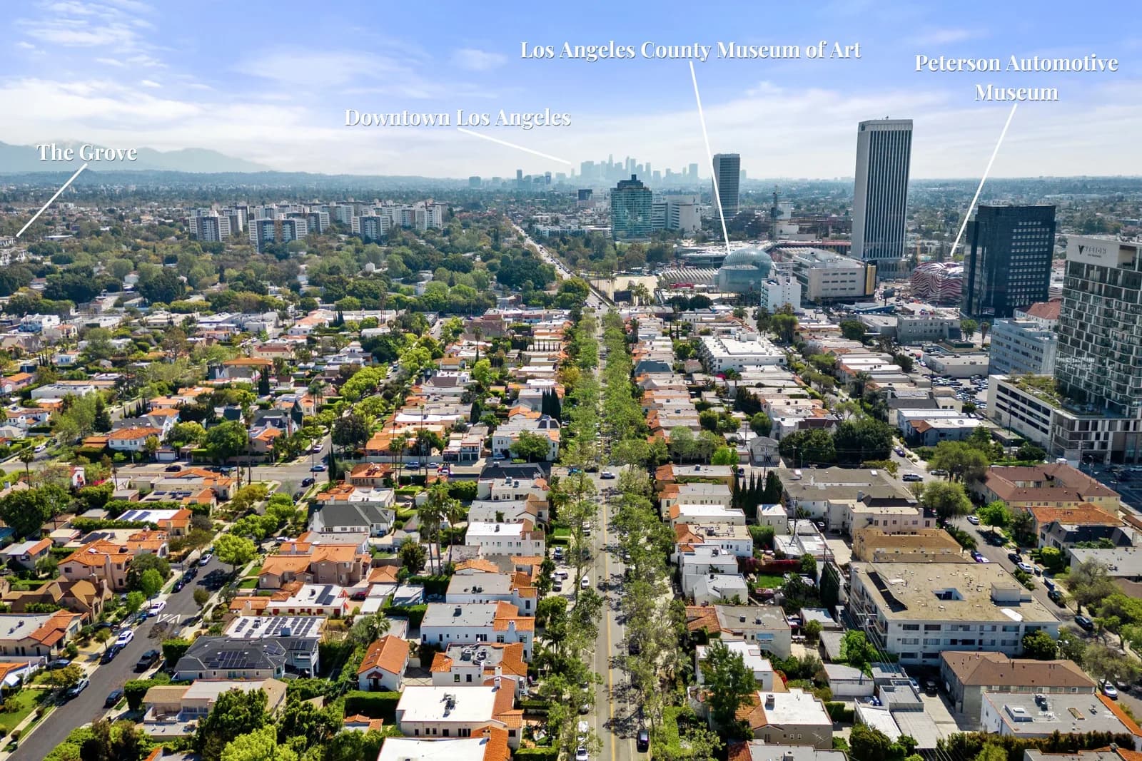 Aerial view of a residential neighborhood with a central avenue leading to the downtown Los Angeles skyline