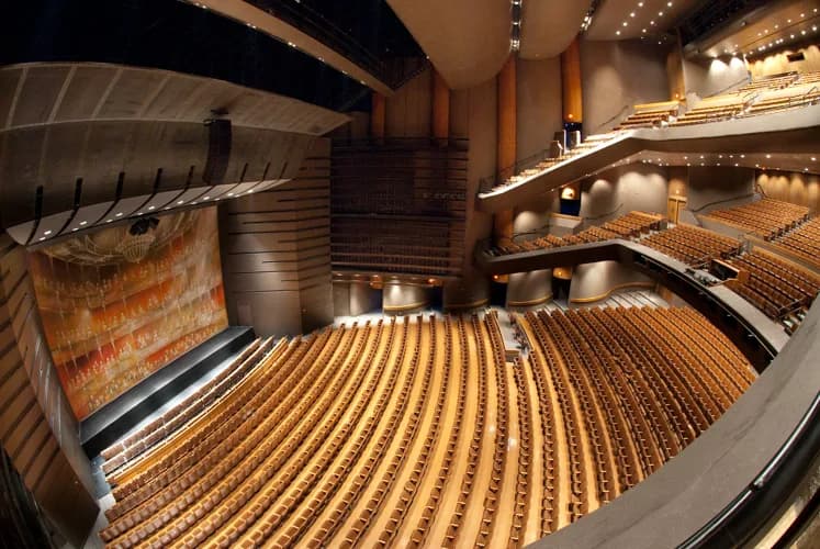 Interior of a large theater with curved rows of brown seats and multiple balconies