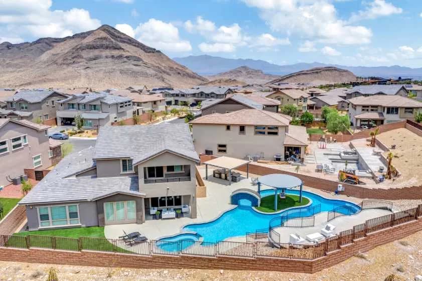 Aerial view of a large residential backyard pool, surrounding houses, with desert mountains in the distance