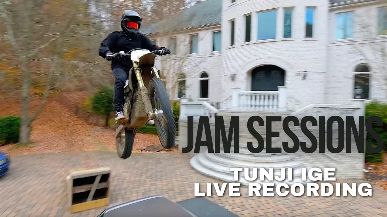 Dirt bike rider mid-air in front of a white mansion with autumn leaves on the ground