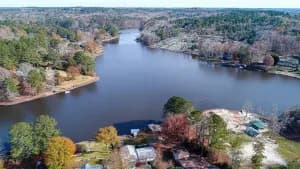 Aerial view of a winding lake edged by forest, with houses along the shoreline