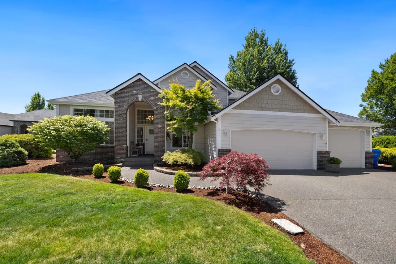 Front view of a suburban house with brick arched entry, a large garage, and manicured landscaping