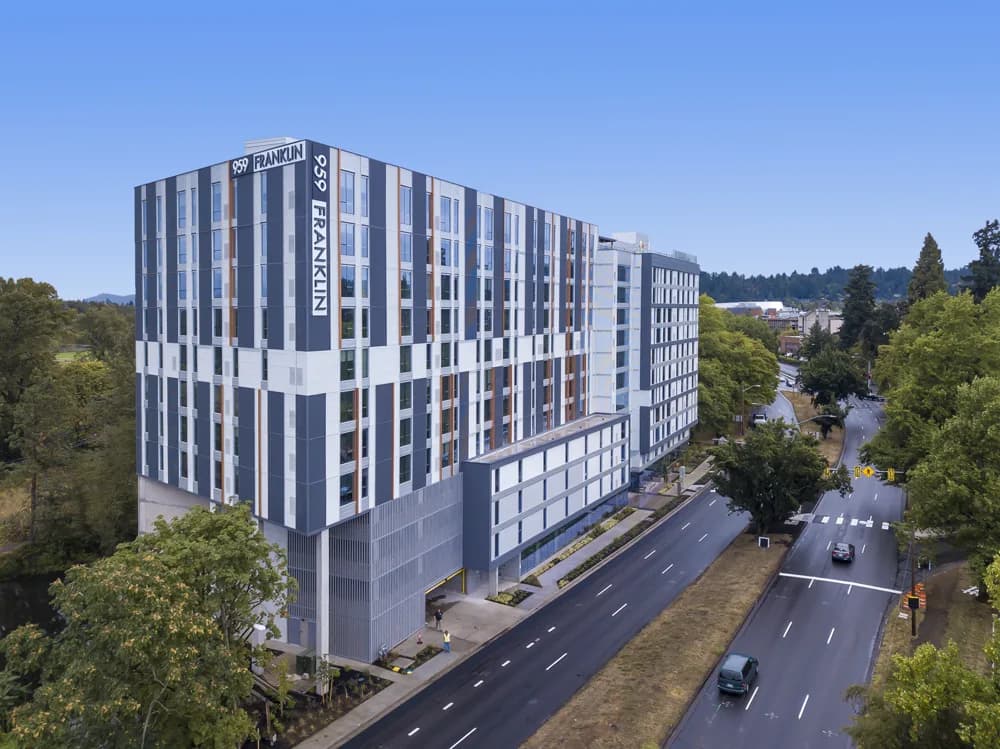 Aerial view of a modern blue-gray building with vertical panels and FRANKLIN signage along a street