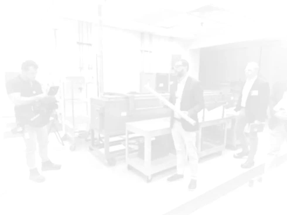 Several people stand around a large industrial machine in a bright room