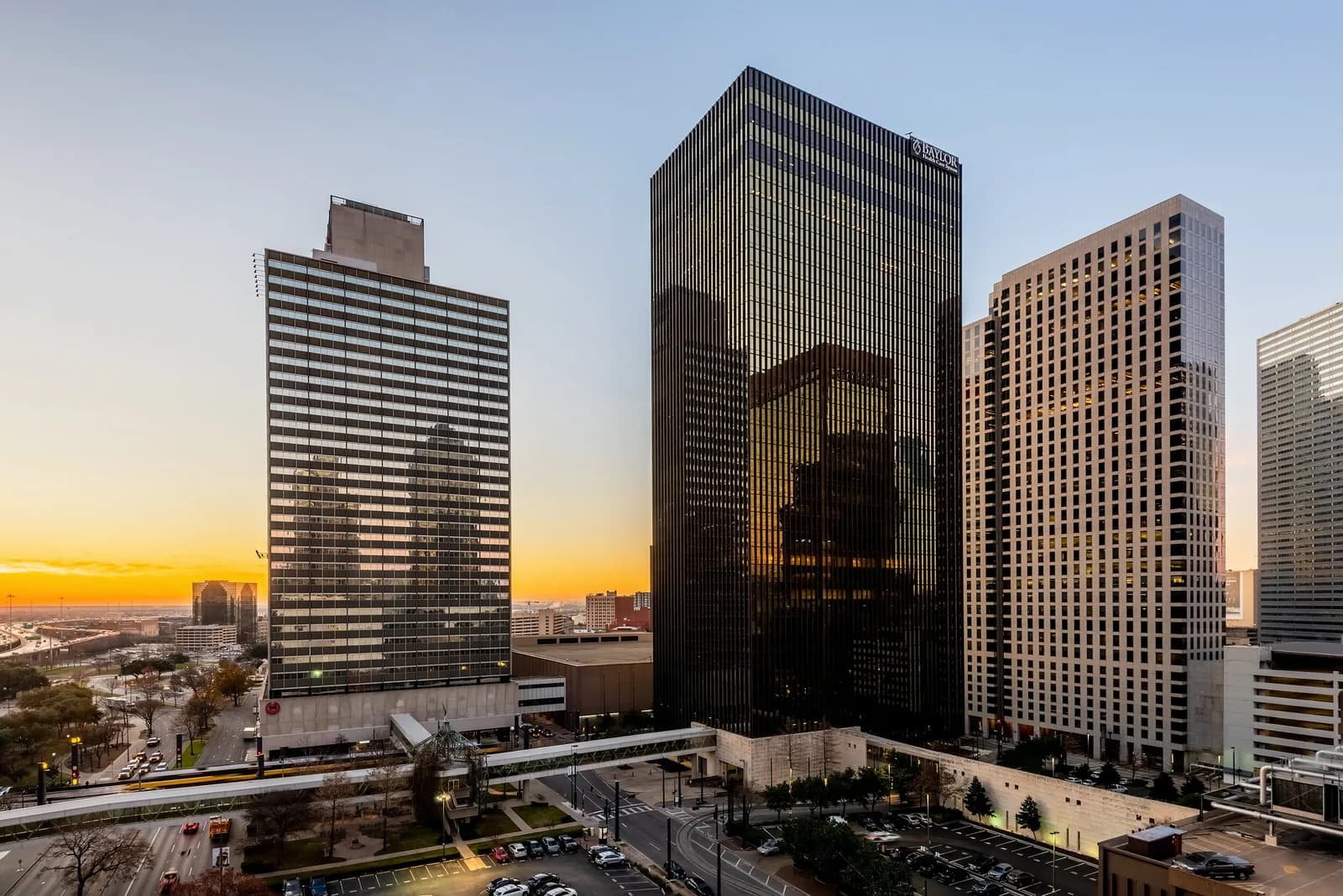 City skyline at sunset with tall glass office towers and streets below